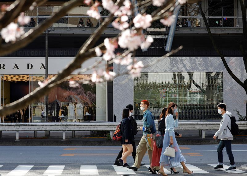 &copy; Reuters. Pedestres de máscara em rua de Tóquio