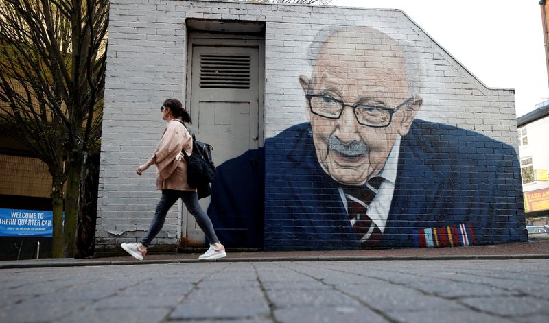 &copy; Reuters. A woman walks past a new mural of British veteran and fundraiser Captain Tom Moore by artist Akse-P19   amid the outbreak of the coronavirus disease (COVID-19) in Manchester