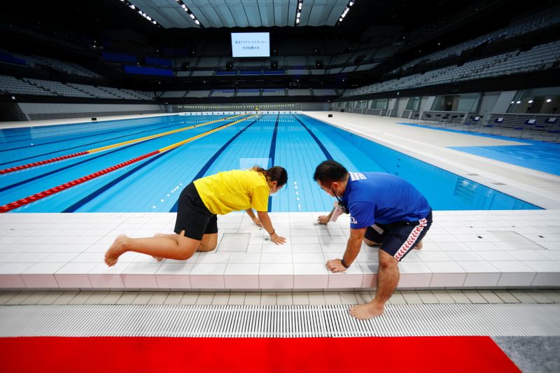 &copy; Reuters. FILE PHOTO: Staff members work next to the swimming pool of the Tokyo Aquatics Centre, in Tokyo