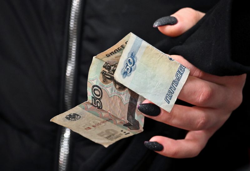 &copy; Reuters. A customer holds a Russian 50-rouble banknote in a grocery store in Omsk
