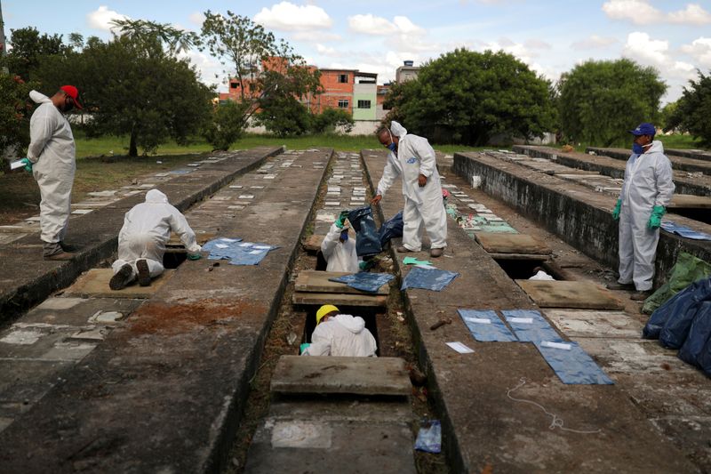 &copy; Reuters. Funcionários com trajes de proteção fazem exumações no cemitério de Vila Nova Cachoeirinha, em São Paulo