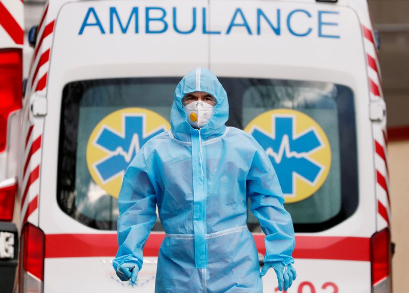 &copy; Reuters. Profissional de saúde com trajes de proteção em frente a ambulância do lado de fora de hospital em Kiev, na Ucrânia