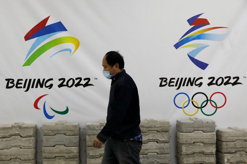 &copy; Reuters. FILE PHOTO: Man walks past a board with logos of 2022 Winter Olympic Games, at a souvenir shop under renovation in Beijing