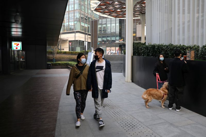 &copy; Reuters. Married couple Liu Zhichang and Yu Tao walk at a plaza after they finished gym class in Beijing