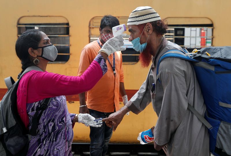 &copy; Reuters. Profissional de saúde checa temperatura e pulso de passageiro em estação ferroviária de Mumbai, na Índia