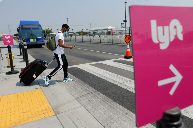 © Reuters. FILE PHOTO: Traveler arrives as Uber and Lyft drivers demonstrate over basic employee rights in California