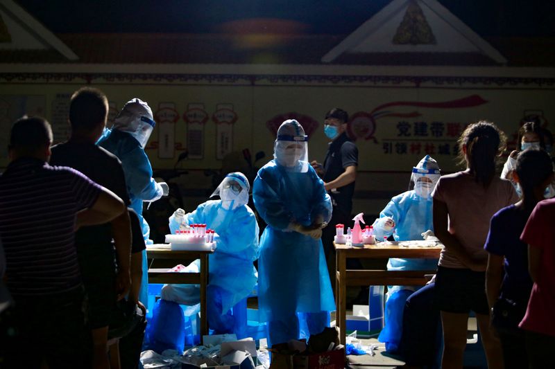 &copy; Reuters. FILE PHOTO: Medical workers attend to people lining up for nucleic acid testing at a residential compound in Ruili