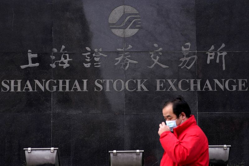 &copy; Reuters. FILE PHOTO: A men wearing a mask walk at the Shanghai Stock Exchange building at the Pudong financial district in Shanghai