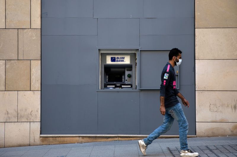 &copy; Reuters. FILE PHOTO: A man wearing a face mask walks past a fortified ATM machine in Beirut