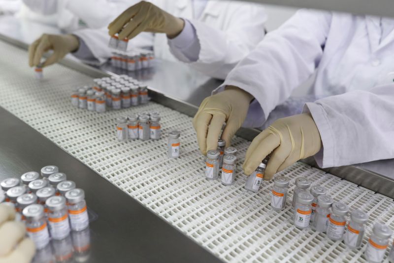 &copy; Reuters. FILE PHOTO: Workers place Sinovac COVID-19 vaccine vials in trays at Butantan biomedical production center