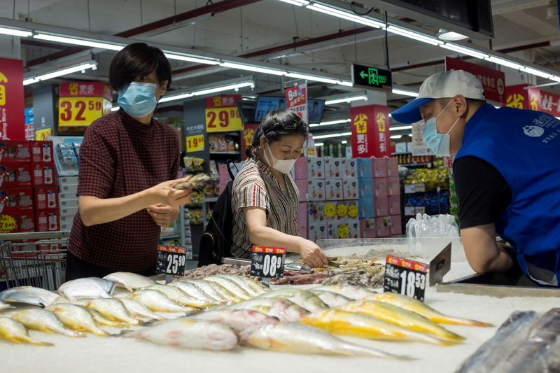 © Reuters. FILE PHOTO: People look at fresh seafood in a supermarket in Beijing