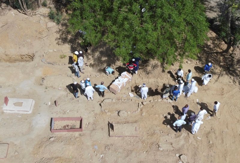 &copy; Reuters. Una imagen tomada con un dron muestra a los familiares esperando antes de enterrar los cuerpos de los hombres que murieron debido a la enfermedad del coronavirus (COVID-19), en un cementerio de Nueva Delhi, India