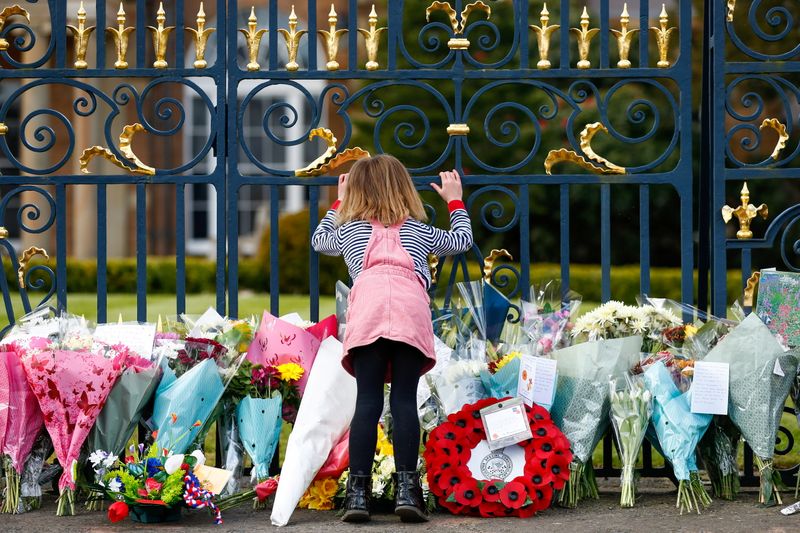 &copy; Reuters. Una nilma mira por la reja del Castillo de Hillsborough junto a las flores depositadas en memoria del príncipe Felipe, en Hillsborough, Irlanda del Norte.