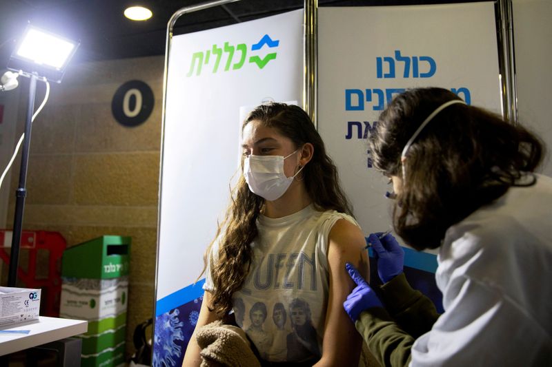 © Reuters. FILE PHOTO: A youth receives a vaccination against the coronavirus disease (COVID-19) at a temporary Clalit healthcare maintenance organisation (HMO) centre, at a sports arena in Jerusalem