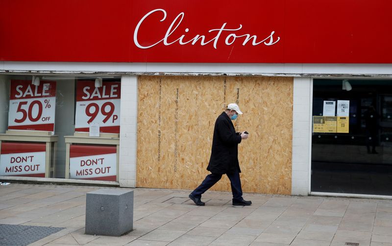&copy; Reuters. FILE PHOTO: A man wearing a face mask walks past a boarded up retail unit in Preston