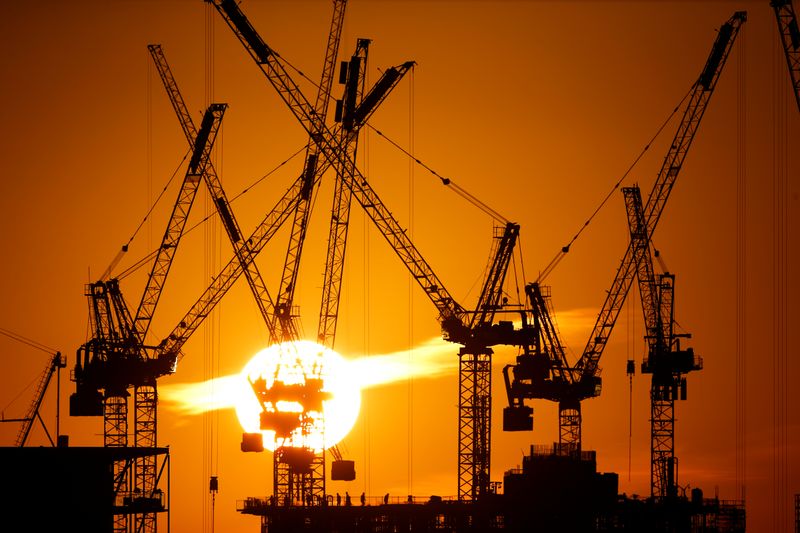 © Reuters. Workers are seen as the sun sets behind a construction site in London