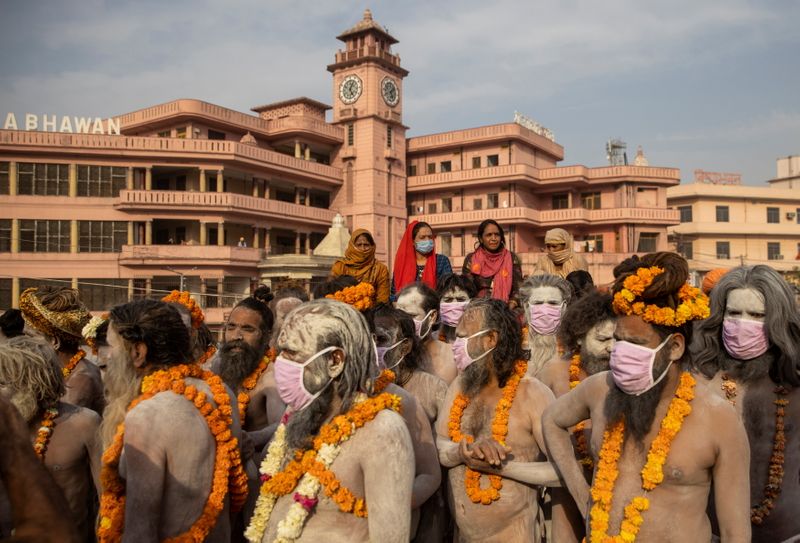 © Reuters. Naga Sadhus, or Hindu holy men wearing face masks wait before the procession for taking a dip in the Ganges river during Shahi Snan at 