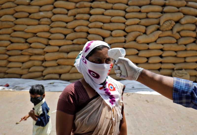 &copy; Reuters. Profissional de saúde checa temperatura de funcionária de unidade beneficiadora de arroz na vila de Bavla, nos arredores de Ahmedabad, na Índia
