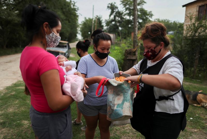 &copy; Reuters. Voluntaria entrega una ración de guiso a personas de escasos recursos en un recipiente de plástico en un comedor social organizado en la casa de Aida Mariela Unayche, en Manzanares