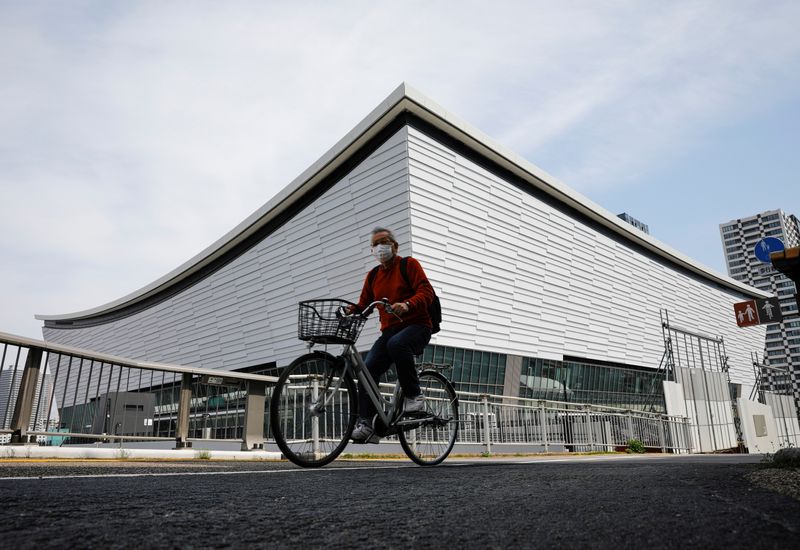 &copy; Reuters. A man wearing a protective mask amid the coronavirus disease (COVID-19) outbreak, cycles past Ariake Arena  in Tokyo