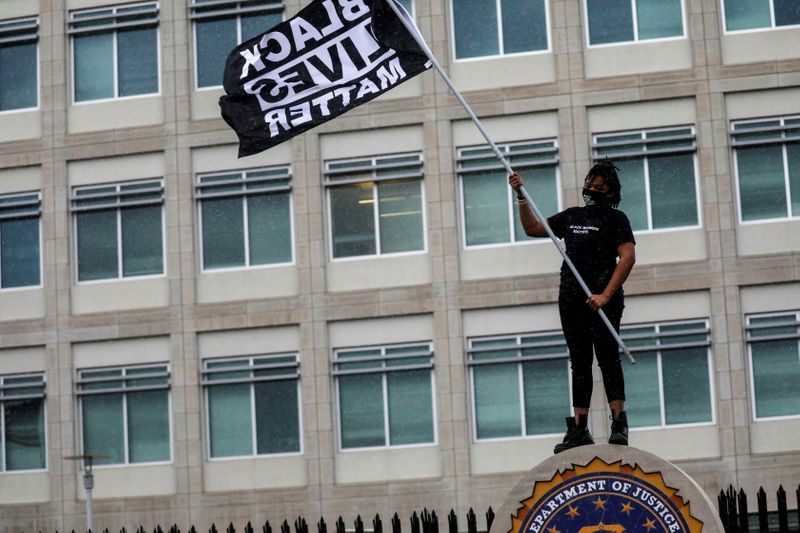 &copy; Reuters. FILE PHOTO: A protester carries a Black Lives Matter flag outside the Federal Bureau of Investigation Minneapolis Division field office, days after Daunte Wright was shot and killed by a police officer, in Brooklyn Center, Minnesota