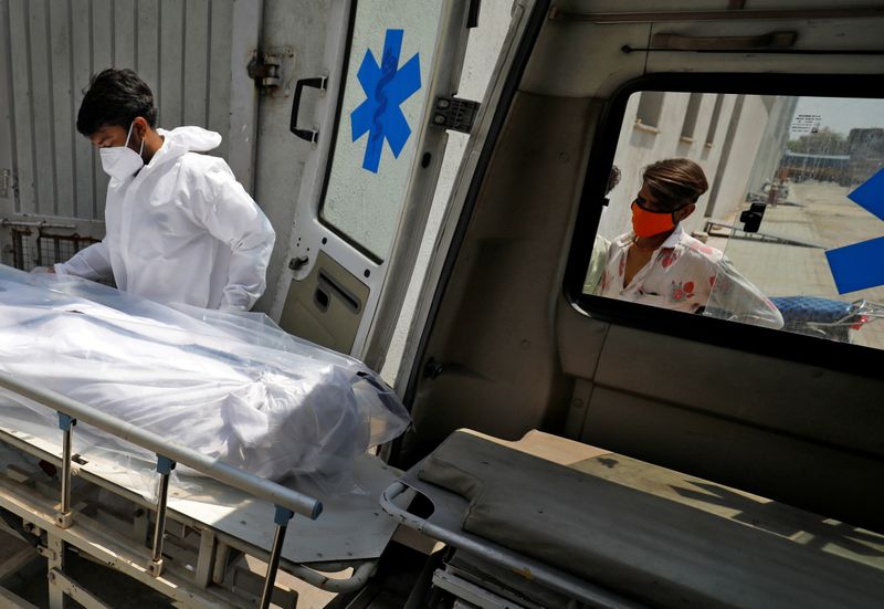 &copy; Reuters. Profissional de saúde coloca corpo de homem que morreu de Covid-19 em ambulância em hospital de Ahmedabad, na Índia