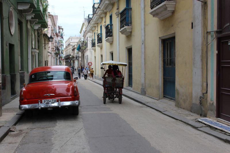 &copy; Reuters. FILE PHOTO: A bicycle taxi passes by a parked vintage American car in Havana