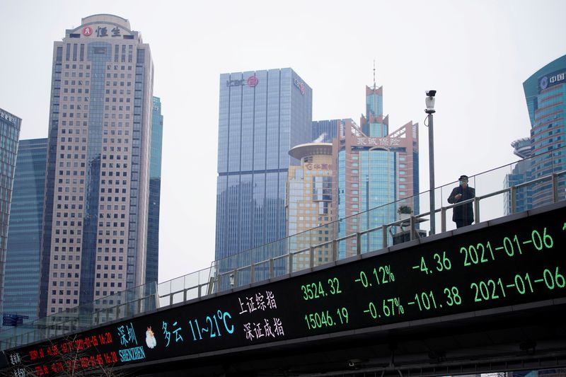 © Reuters. FILE PHOTO: A man stands on an overpass with an electronic board showing Shanghai and Shenzhen stock indexes in Shanghai