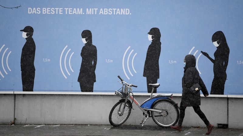 &copy; Reuters. FILE PHOTO: A woman walks next to a poster reading &quot;The best team. With distance.&quot; in front of a BMW factory as the spread of the coronavirus disease (COVID-19) continues in Munich
