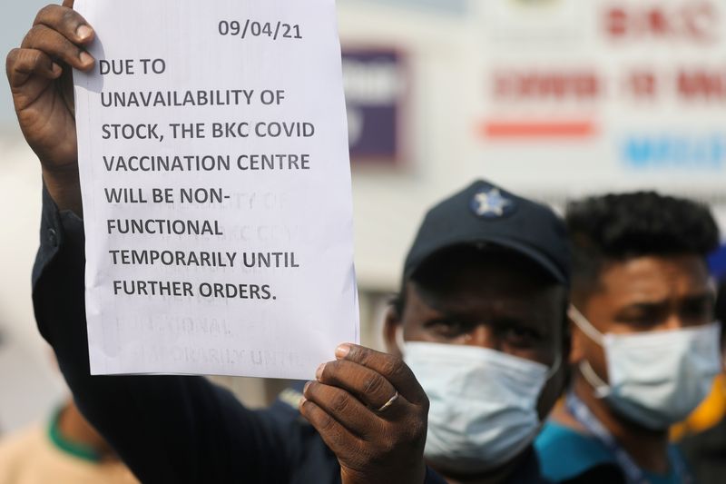 &copy; Reuters. FOTO DE ARCHIVO: Un hombre sostiene un papel en el que se informa en inglés sobre la escasez de existencias de vacunas de COVID-19 en un centro de vacunación de Bombay