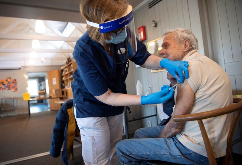 &copy; Reuters. Un&apos; operatrice sanitaria vaccina un anziano con il vaccino Pfizer in una chiesa a Stoccolma