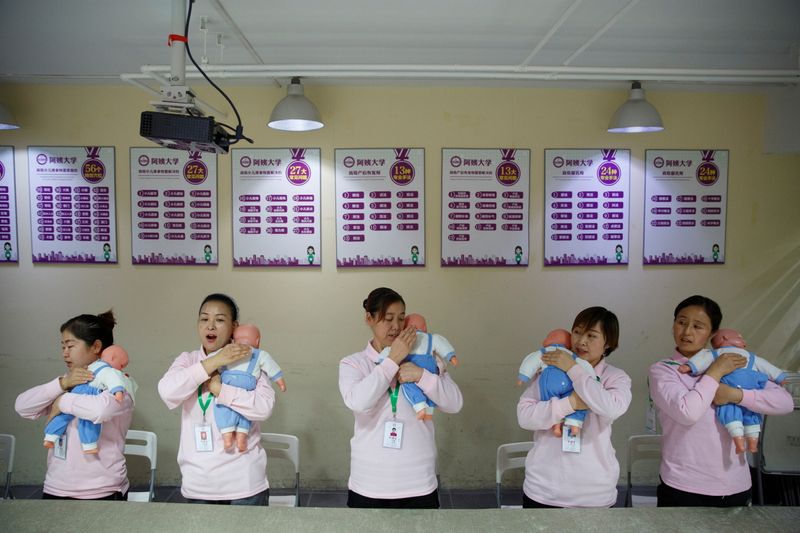 &copy; Reuters. FILE PHOTO: Students at Ayi University, a training program for domestic helpers, practice on baby dolls during a course teaching childcare in Beijing