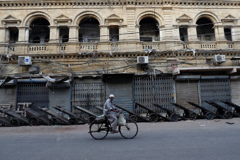 © Reuters. A hawker on bicycle rides past a closed wholesale cloth market during a countrywide strike in Karachi,