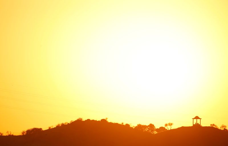 © Reuters. FILE PHOTO: People are silhouetted against the setting sun at 