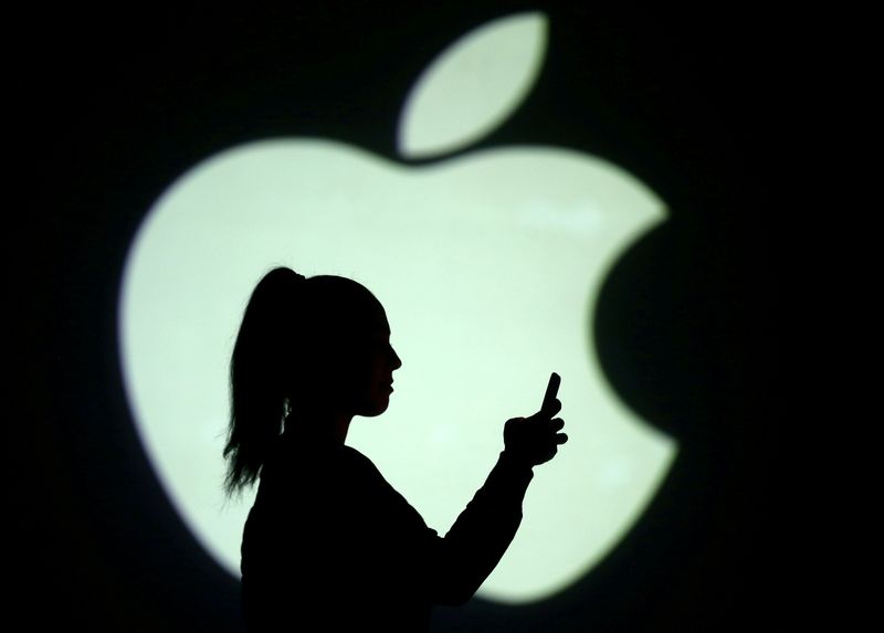 &copy; Reuters. Imagen de archivo ilustrativa de la silueta de una usuaria de un teléfono móvil frente a una pantalla que proyecta el logo de Apple