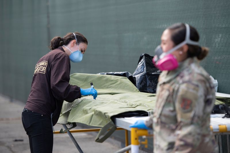 &copy; Reuters. Una trabajadora del Departamento de Médicos Forenses del Condado de Los Ángeles (DMEC) marca una bolsa para cadáveres junto a una agente de la Guardia Nacional de California en una instalación secundaria de almacenamiento refrigerado temporal del DMEC