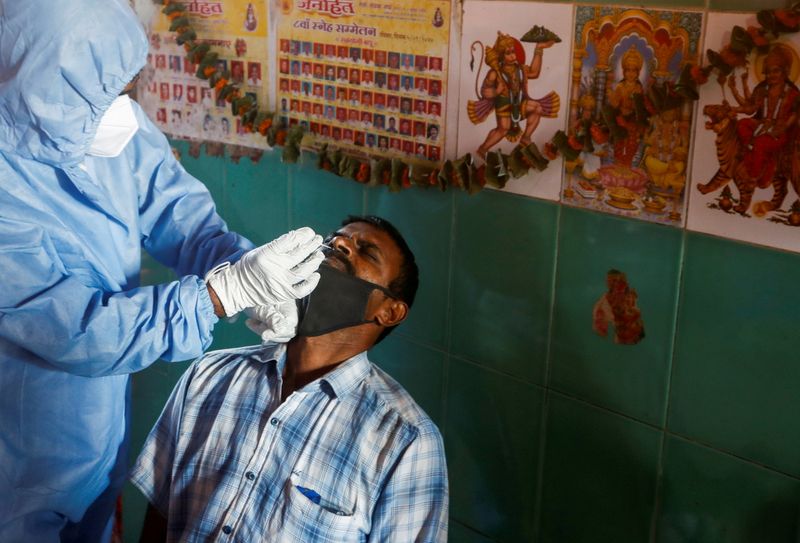 &copy; Reuters. FILE PHOTO: A health worker in personal protective equipment (PPE) collects a swab sample from a man in Mumbai
