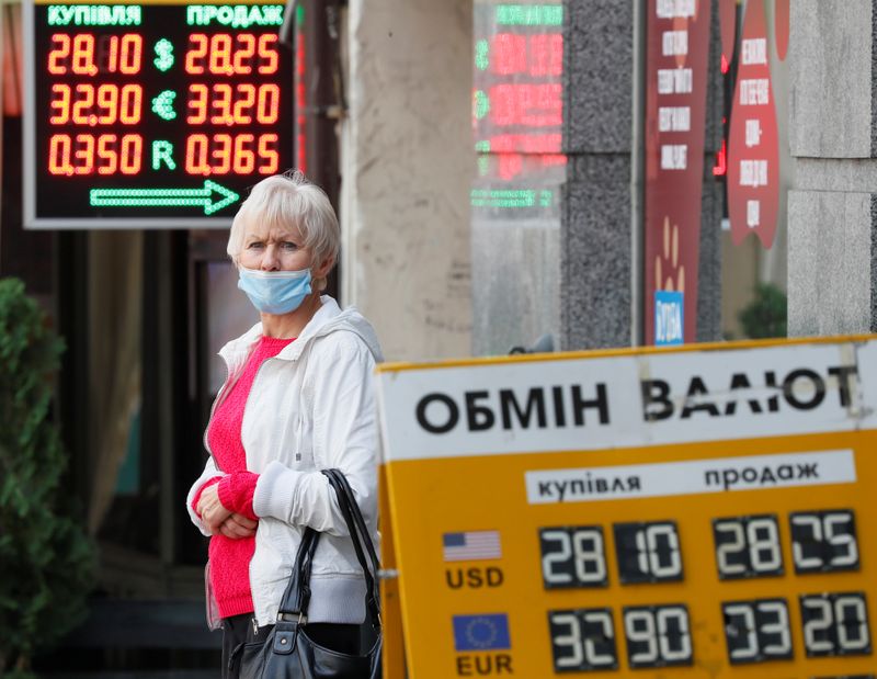&copy; Reuters. A woman wearing a protective face mask stands near a currency exchange office, in Kyiv