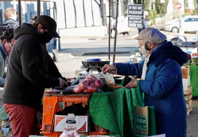 &copy; Reuters. A lady pays for fruit and vegetables from a market stall in Buckingham, Britain