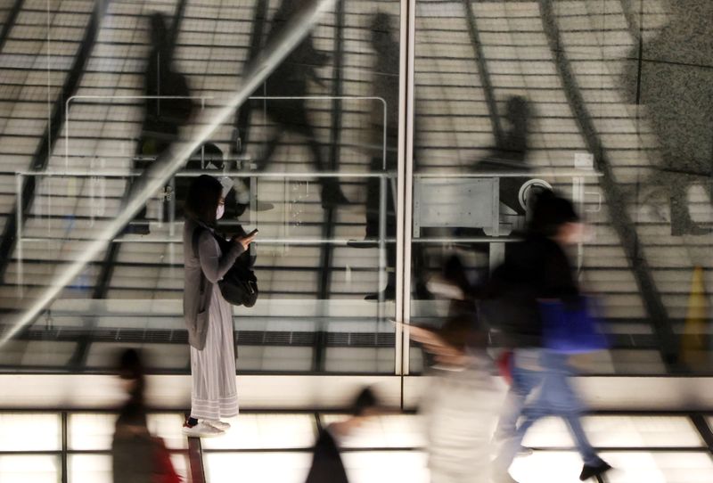 &copy; Reuters. FOTO DE ARCHIVO: Transeúntes con mascarillas caminan por un vestíbulo en Tokio