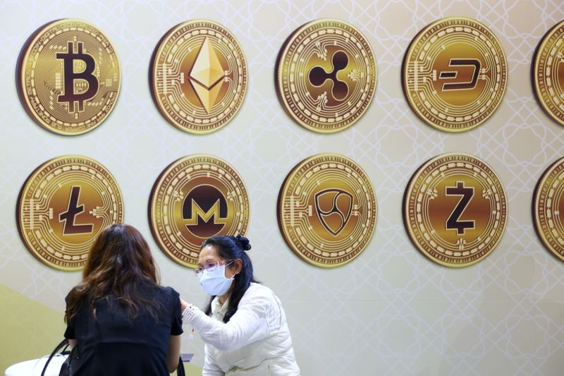 &copy; Reuters. FILE PHOTO: Customers talk against a backboard with signs of cryptocurrency during 2020 Taipei International Finance Expo in Taipei,
