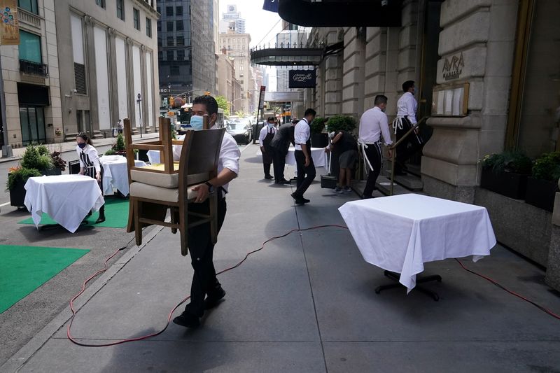 &copy; Reuters. FILE PHOTO: A waiter sets up tables in front of a restaurant on a street on the first day of the phase two re-opening of businesses following the outbreak of the coronavirus disease (COVID-19), in the Manhattan borough of New York City