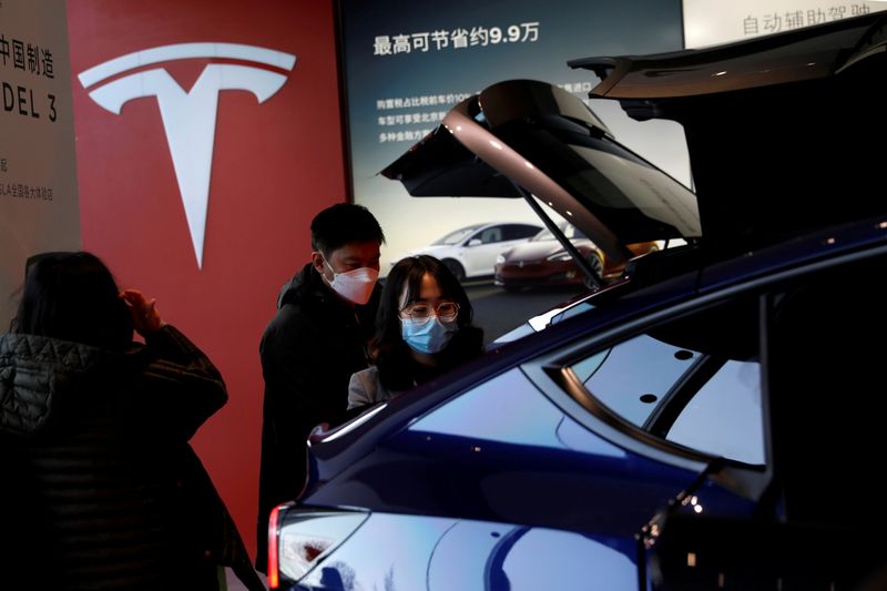 &copy; Reuters. FILE PHOTO: Visitors wearing face masks check a China-made Tesla Model Y sport utility vehicle (SUV) at the electric vehicle maker&apos;s showroom in Beijing