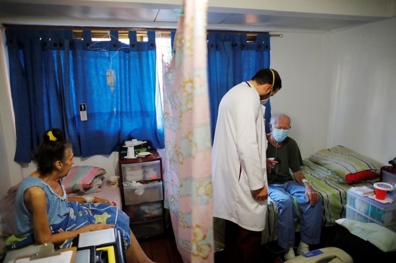 &copy; Reuters. El médico venezolano Leonardo Acosta controla a dos pacientes que están recibiendo atención domiciliaria para el coronavirus en Caracas