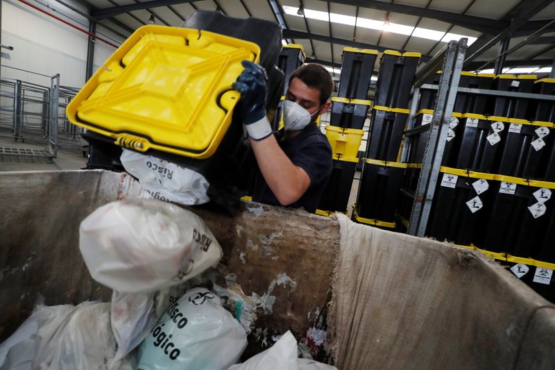 &copy; Reuters. A worker removes used supplies from COVID-19 vaccines and protective equipment from a container in a waste treatment facility in Chamusca, Santarem