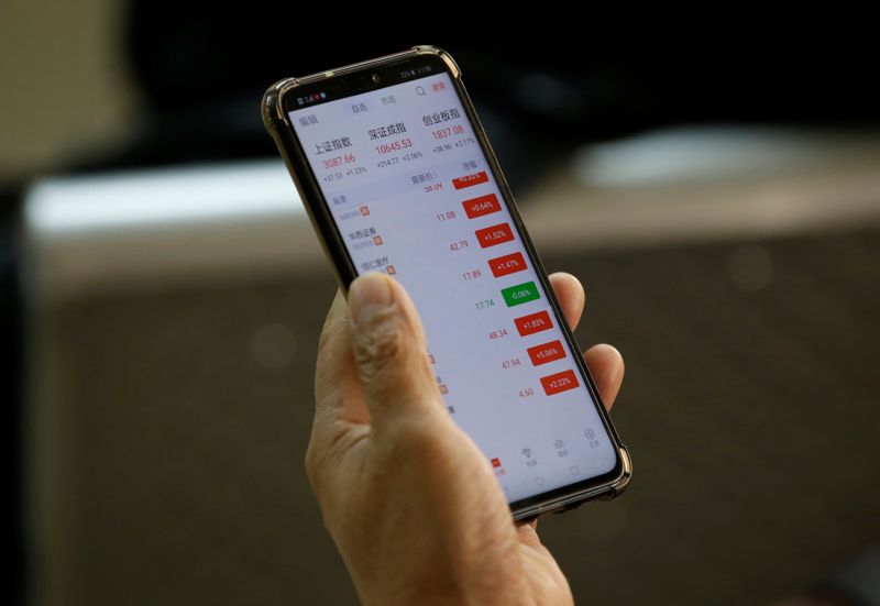 &copy; Reuters. An investor checks share prices on his mobile phone at a brokerage office in Beijing