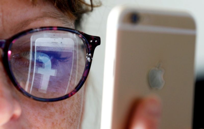 &copy; Reuters. FILE PHOTO: The Facebook logo is reflected on a woman&apos;s glasses in this photo illustration