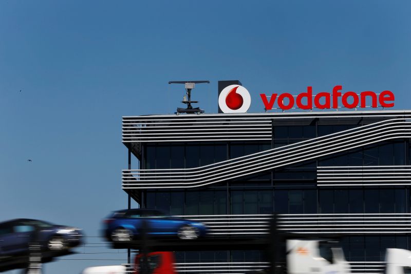 © Reuters. FILE PHOTO: A truck carrying cars speeds past the headquarters of Vodafone in Madrid