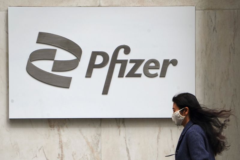 © Reuters. A person walks past a Pfizer logo in New York City