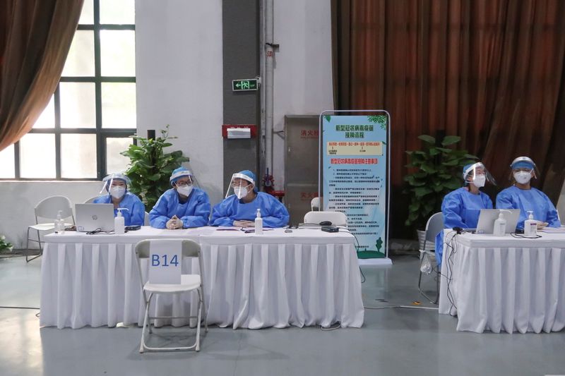 &copy; Reuters. FILE PHOTO: Staff members sit at desks to register people for a shot of a vaccine against the coronavirus disease (COVID-19) at a vaccination center in Beijing